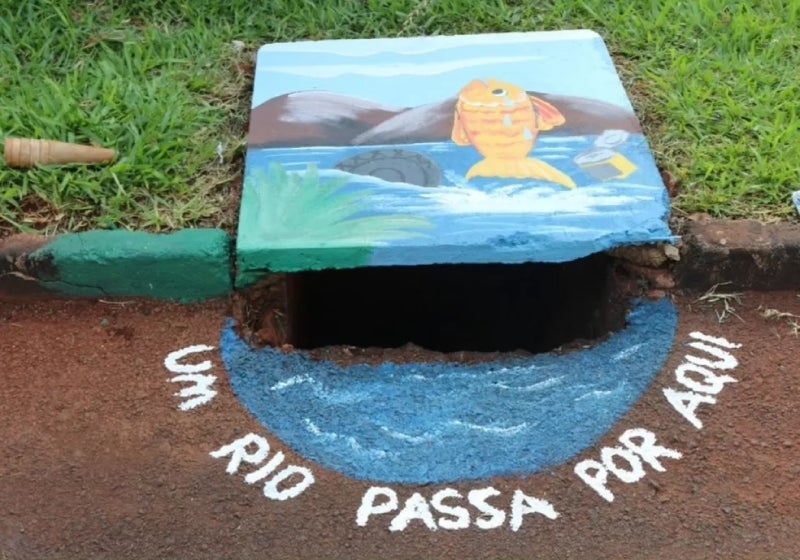 Crianças pintam bueiros para alertar adultos sobre descarte de lixo