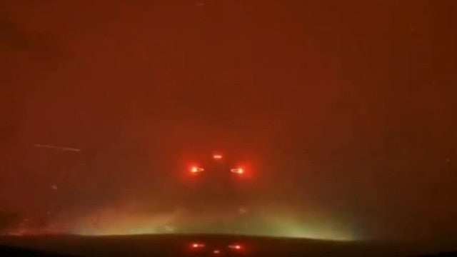 Carro percorre estrada rodeada por incêndio de grande dimensão no Canadá