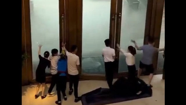 Funcionários de hotel tentam segurar portas na passagem do tufão Yagi